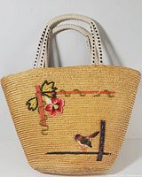 Front and angled view of the vintage wicker tote bag with embroidered flower and bird motif.