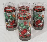 Set of 4 cylindrical vintage beverage glasses with colorful silkscreen fruit patterns arranged closely together on a white surface.