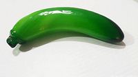 Green banana shaped Murano art glass sculpture shown from one side on white background
