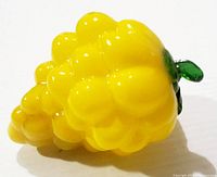 Side view of the vintage Murano yellow grapes art glass figurine showing cluster detail and green leaves.