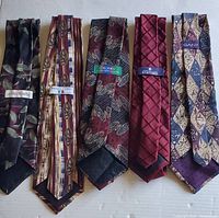 Five vintage ties laid flat showing the front and labels clearly with varying colors and patterns from different brands.