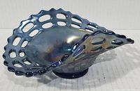 Oblique view of cobalt blue carnival glass bowl showing open edge basket weave pattern and iridescent finish.