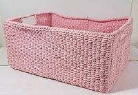 Front and side view of rectangular pink wicker basket with cut-out handles and wood base insert.