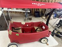 Front angle of the red Step2 two-seat wagon showing seats, canopy, and wheels.
