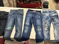 Four pairs of girls jeans laid out flat showing color and distress details.