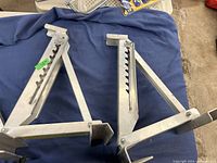 Pair of aluminum ladder jacks laid on blue fabric showing both units side by side and construction details.