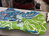 Photo showing the top surface of the sled with colorful blue, white, and green abstract pattern and the brand name 'Arthur'.