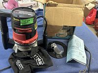 Front view of Craftsman router with dust collection bag, router bit, base plate, and instruction manual all displayed on table.