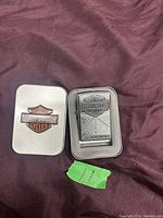 Photo of Harley Davidson Zippo lighter with matching metal case on maroon fabric background