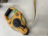 Yellow Johnson 100 ft tape measure with crank reel, showing overall condition and design.