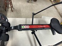 Side and top view of the Lanos rowing machine showing the seat, handlebars, and footrests on a white surface in a workshop or storage area.