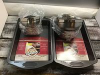 Two Wilton rectangular non-stick baking pans each 13 x 9 x 2 inches, with wrapped metal mixing bowls placed on top.