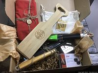 BBQ box with wooden paddle, metal grill tools, apron, and packaging in box.
