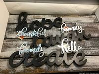 Photo of black wooden and white/iridescent acrylic crafting words laid on wooden surface, showing all words in good condition.