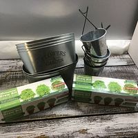 Lot contents showing 4 small metal hanging buckets, 2 rectangular metal containers with text 'FLOWERS & GARDEN', and 2 microgreen grow kits in boxes.