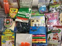 Photo showing complete assortment of kids crafting supplies stacked to display all included items such as crayons, markers, craft kits, and small containers.