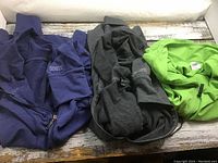 Three sweaters laid side by side showing two Roots hoodies (navy blue and charcoal gray) and one bright green Danskin hoodie all size XL.