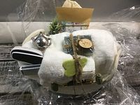 Full spa basket with all contents wrapped in cellophane, showing basket, face cloths, soap, candle holder, and tea