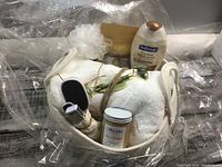Spa basket containing white towel, green jade roller massager, Softsoap body wash, pedicure tools, bath sponge, herbal tea, all wrapped in clear cellophane.