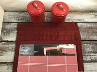 Set of items including red table runner, four red placemats, and two red metal tins with lids labeled sugar and tea.