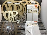 Wood craft pieces arranged showing different 'LOVE' cutouts, large circles, and decorative wooden shapes.