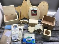 Full display of sixteen wooden craft pieces including various shapes and small boxes with sanding sponges included.