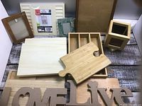 Overview of 13 wooden craft items arranged on a surface including various frames, trays, puzzle piece shape, decorative words, and a pen holder box with drawer.