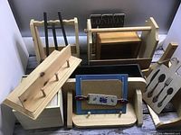 Overall view of assorted wood craft totes, shelves, and decorative pieces including corkboard and utensil themed item.