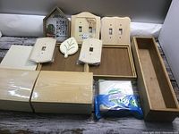 Lot items displayed on a surface showing 2 wooden treasure chests, wooden frames, plaques, and switch plates in natural wood finish.