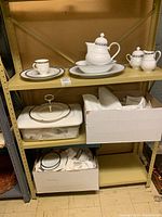 Three-tier shelving with boxed and unboxed Noritake china sets