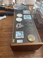 Top-down angled view of the coffee table showing smoked glass top with various decorative items arranged on it, wood frame and lower shelf visible.