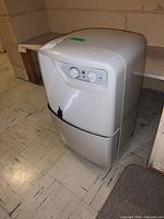 Front view showing control knobs and water collection bucket with minor surface blemish.