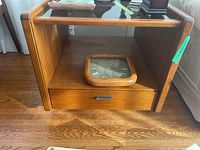Full front view of wood end table with smoked glass top, drawer, and storage cubby containing a wall clock (clock not included)