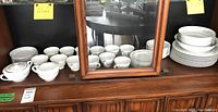 Wide view of displayed Rose China pieces on wooden surface showing cups, saucers, and plates in matching floral design.