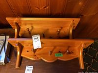 Photo showing two matching wooden wall shelves with four round pegs each, stacked horizontally.