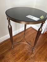 Full view of round side table showing metal frame with antique bronze finish and black stone top.