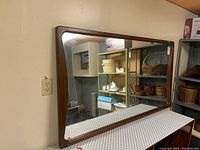Angled front view showing entire mirror and wood frame against wall
