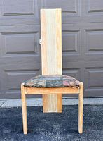 Straight-on front view of the wooden high back chair showing its tall backrest and floral seat upholstery with wear.