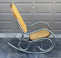 Side view of vintage rocking chair showing chrome tubular frame and woven cane seat and backrest on wooden frames.