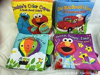 Four soft cloth books with Sesame Street characters and educational themes shown together