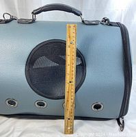 Side view of blue fabric pet carrier measuring about 18 inches tall with circular mesh ventilation holes and zipped compartments.