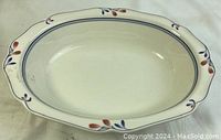 Top view of the Noritake Copper Bud oval serving bowl showing cream-colored base with blue and reddish-brown floral pattern at the rim.