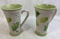Pair of garden-themed ceramic mugs with botanical art and nature quotes, placed side by side showing full design.