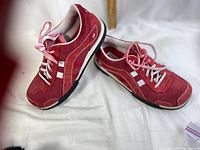 Left and right red suede Skechers shoes showing exterior and sole edges.