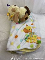 Full view of Taggies children's blanket with multicolored polka dots, giraffe applique, and attached stuffed dog toy.