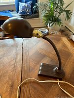 Side view of the vintage Crown gooseneck lamp on a wooden table, showing the lamp shade and flexible neck