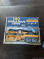 Box of 140 double drape Christmas lights showing house exterior with lights decorated.