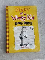 Front cover of Diary of a Wimpy Kid Dog Days showing yellow hardcover with the cartoon character and title clearly visible.