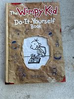 Front cover of 'The Wimpy Kid Do-It-Yourself Book' by Jeff Kinney, showing worn edges and cartoon illustrations around the title.
