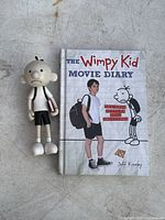 Photo showing the Wimpy Kid Movie Diary book with the Greg Heffley figure beside it.